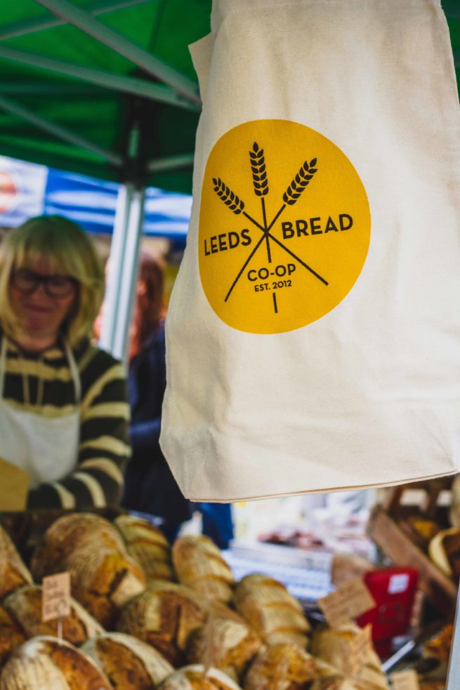 A Leeds Bread Co-op tote bag hanging at the front of a market stall