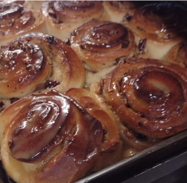 A tray of baked Vegan Salted Caramel and Pecan Swirls which are light brown in colour and glazed.